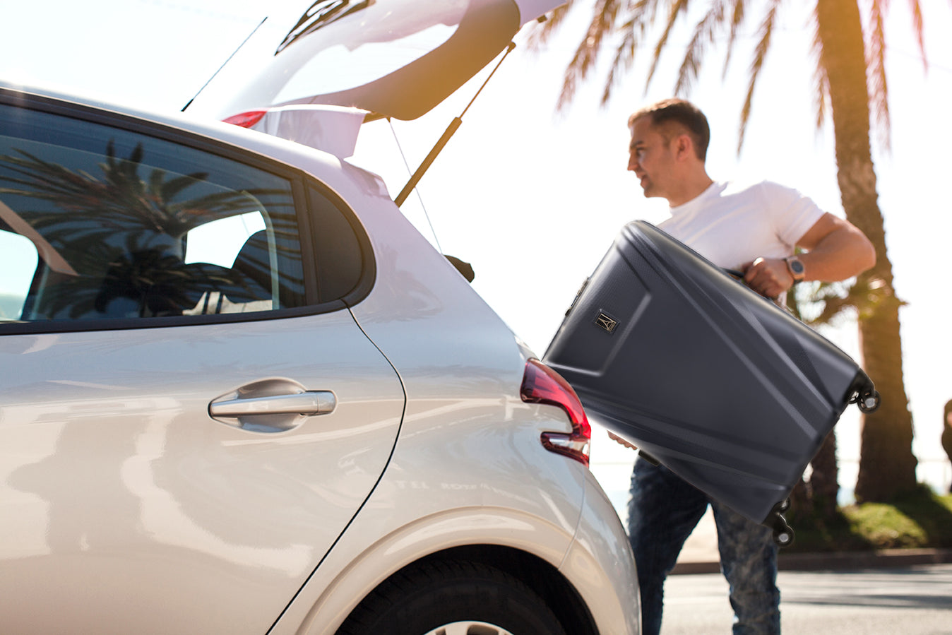 Man placing suitcase in the trunk of his car 
