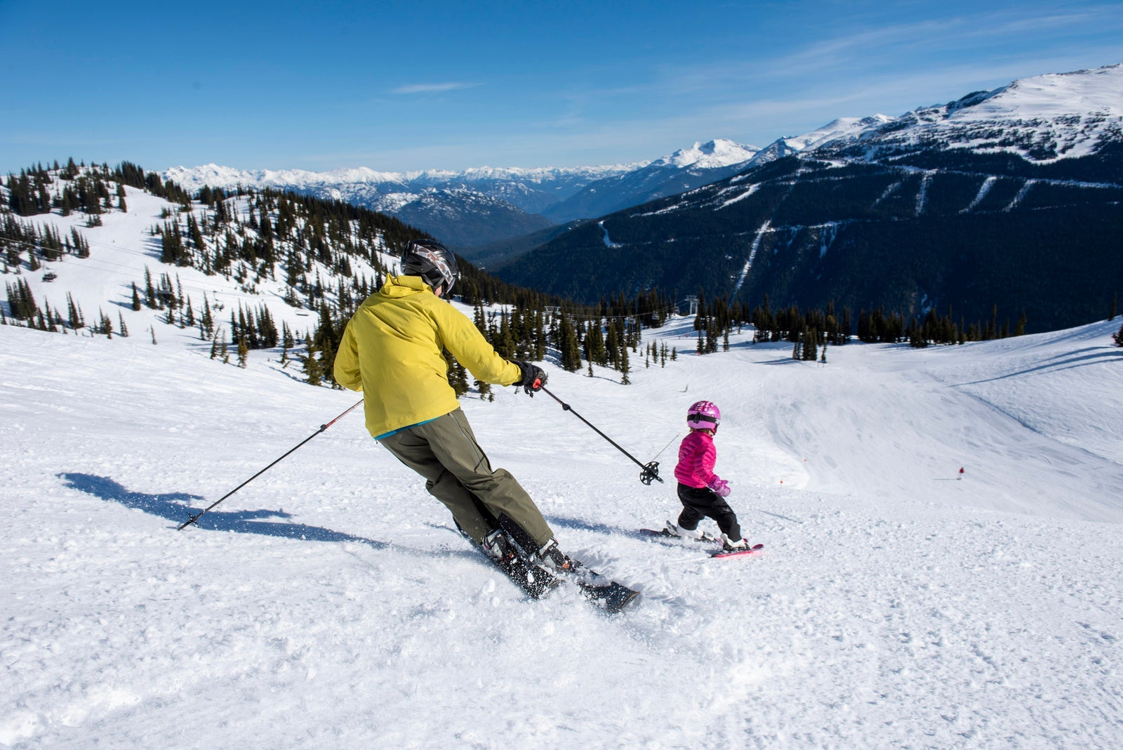 Man and daughter skiing down a mountain