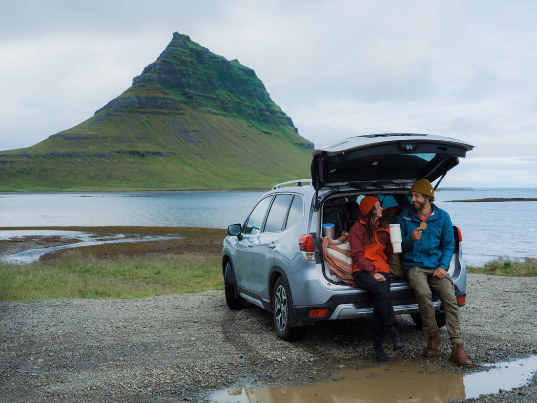 two people on a vacation sitting in the trunk of their car