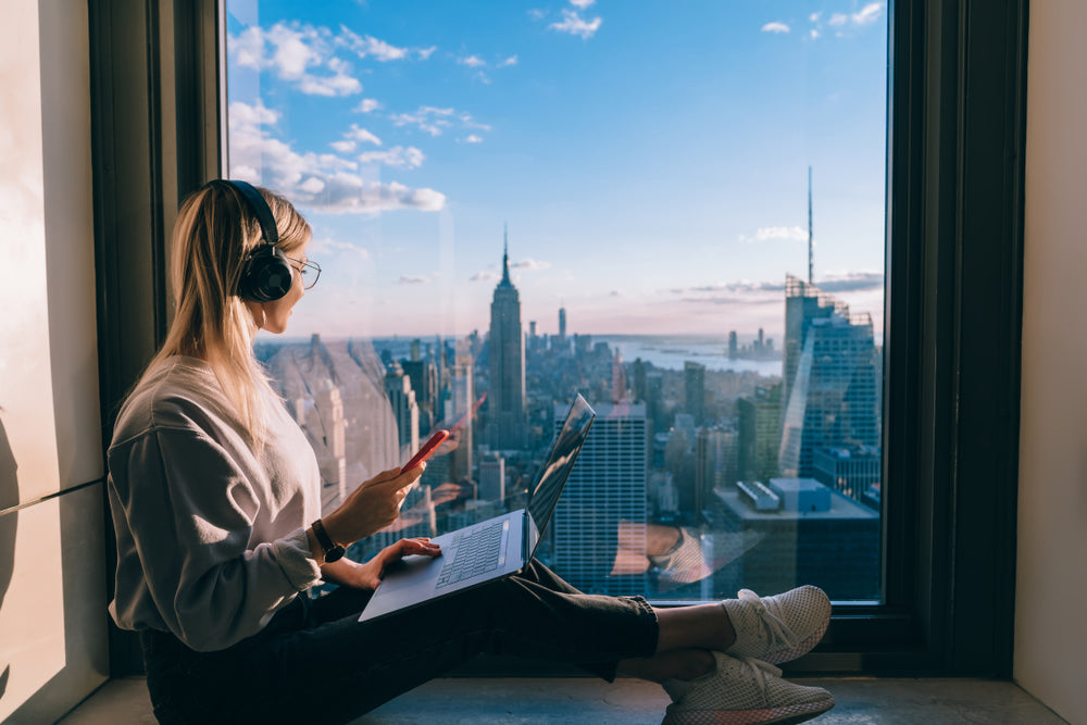 Girl sitting by a window overlooking NYC