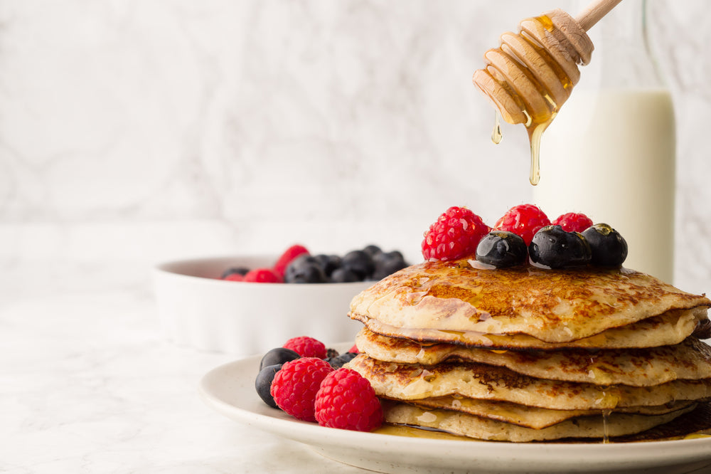 ,homemade classic american pancakes with fresh berry and honey. Sweet homemade pancakes with fruits on white plate