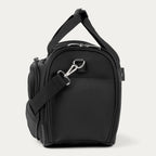 Side view of black tote with a shoulder strap on a white background 
