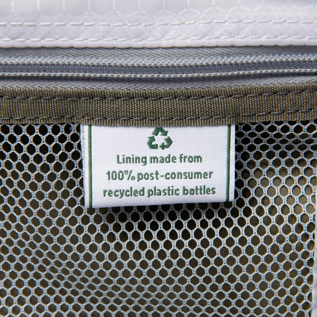close up of the interior fabric tag on the slate green travelpro maxlite 5 large check-in spinner showing a green recycling symbol and text stating lining made from 100 percent post consumer recycled plastic bottles.