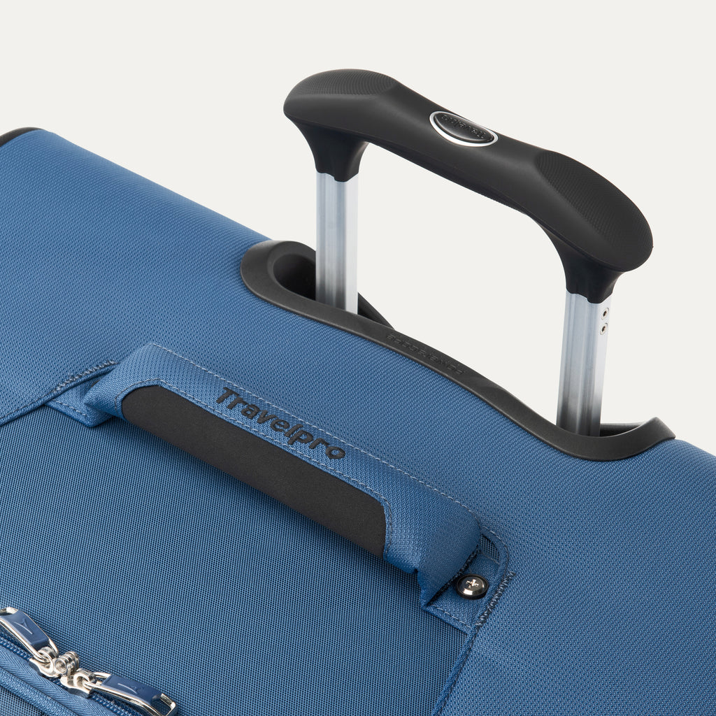 close up of the ensign blue travelpro maxlite 5 large check-in spinner showing the ergonomic contour grip on the powerscope lite handle and the cushioned top carry handle with travelpro branding.