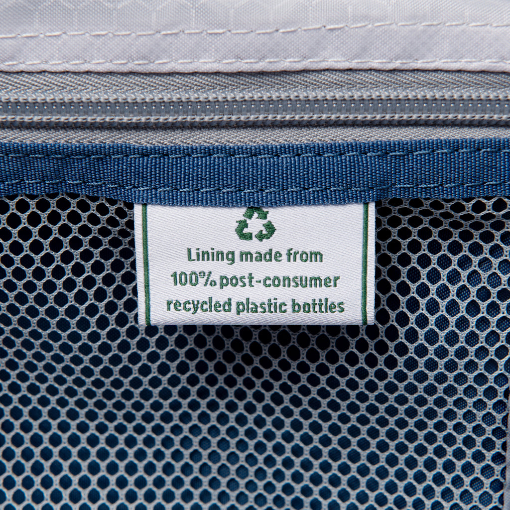 close up of the interior fabric tag on the ensign blue travelpro maxlite 5 large check-in spinner showing a green recycling symbol and text stating lining made from 100 percent post consumer recycled plastic bottles.