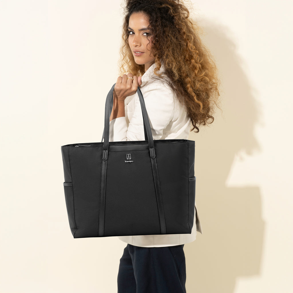 Woman carrying a Travelpro® Crew™ Executive Choice™ 3 Women’s Tote in black over her shoulder.

