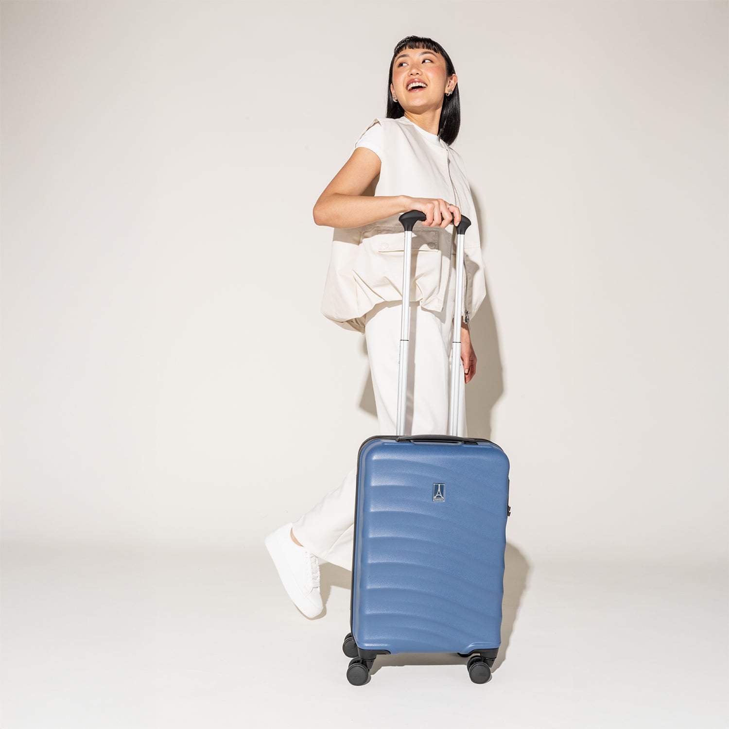Person walking with the Travelpro Maxlite Air Carry-On Hardside Spinner in Ensign Blue, highlighting lightweight maneuverability.
