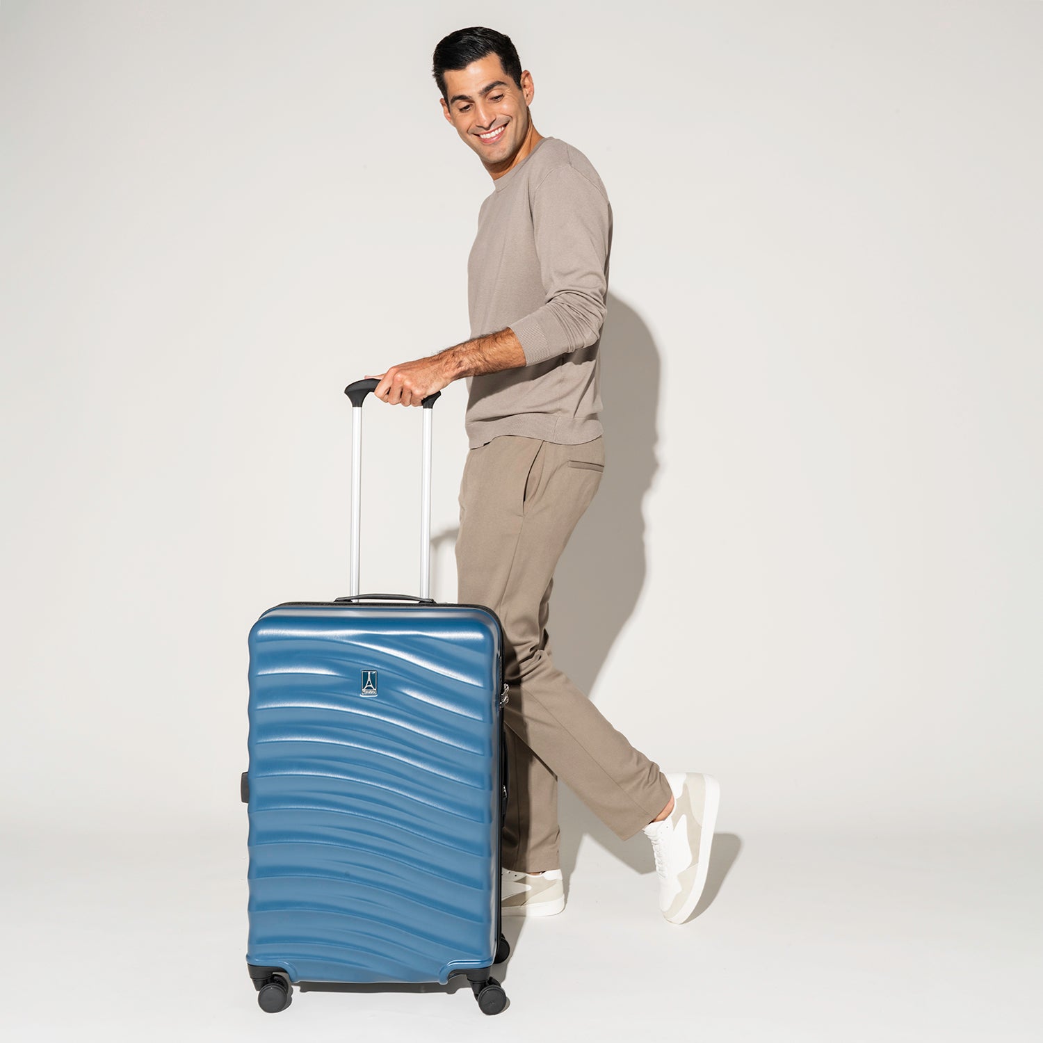 Person walking with the Travelpro Maxlite Air Medium Check-In Hardside Spinner in Teal, featuring 360° spinner wheels.

