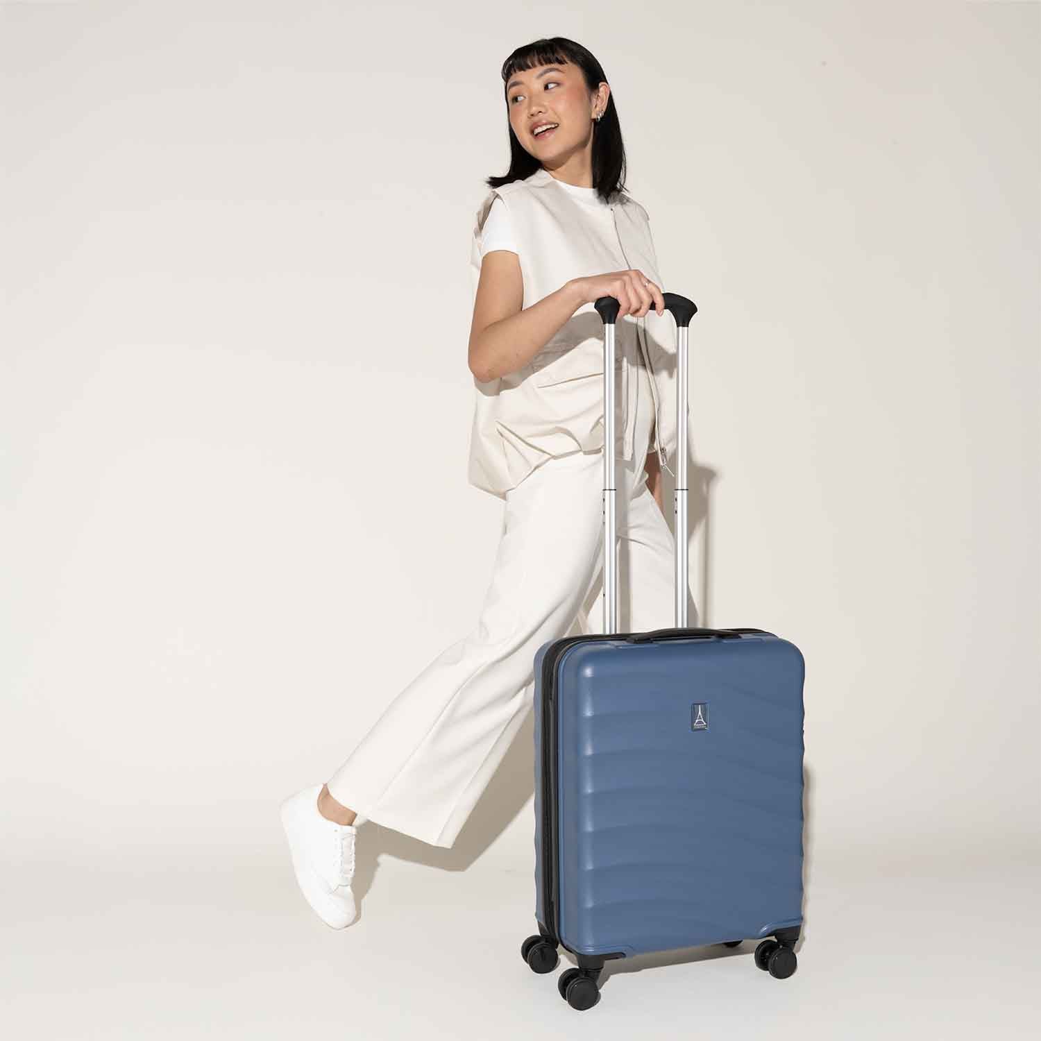 Person stepping forward with the Travelpro Maxlite Air International Carry-On Hardside Spinner in Ensign Blue, designed for lightweight mobility.

