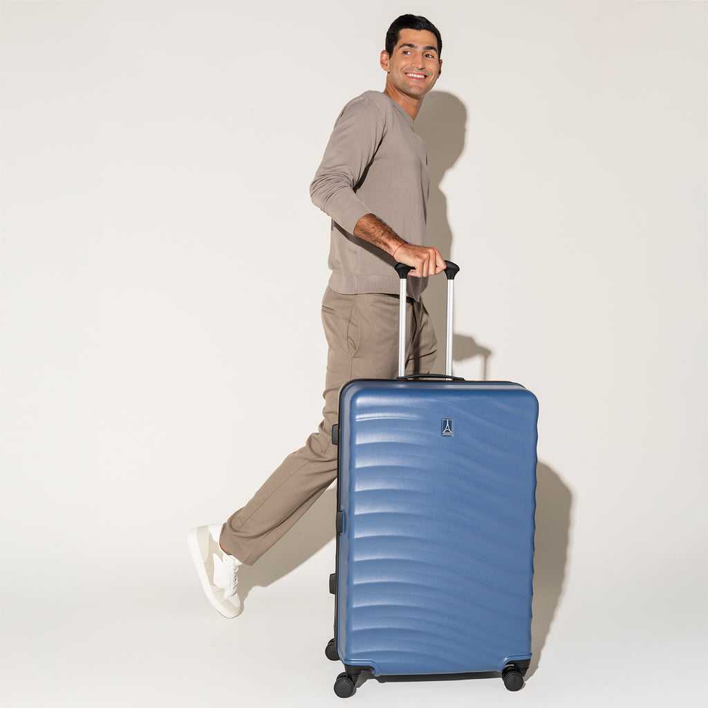 Person striding with the Travelpro Maxlite Air Large Check-In Hardside Spinner in Ensign Blue, built for smooth, stylish travel.
