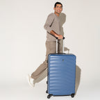 Person striding with the Travelpro Maxlite Air Large Check-In Hardside Spinner in Ensign Blue, built for smooth, stylish travel.
