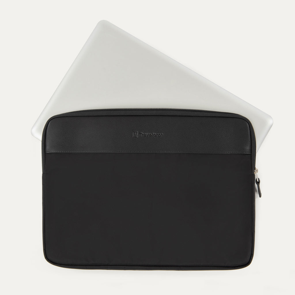 Travelpro® Essentials™ 13"/14" Laptop Sleeve in Black, shown with a laptop partially inserted to highlight its slim, protective fit, featuring a leather-accented top panel and secure side zipper closure.
