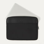 Travelpro® Essentials™ 13"/14" Laptop Sleeve in Black, shown with a laptop partially inserted to highlight its slim, protective fit, featuring a leather-accented top panel and secure side zipper closure.
