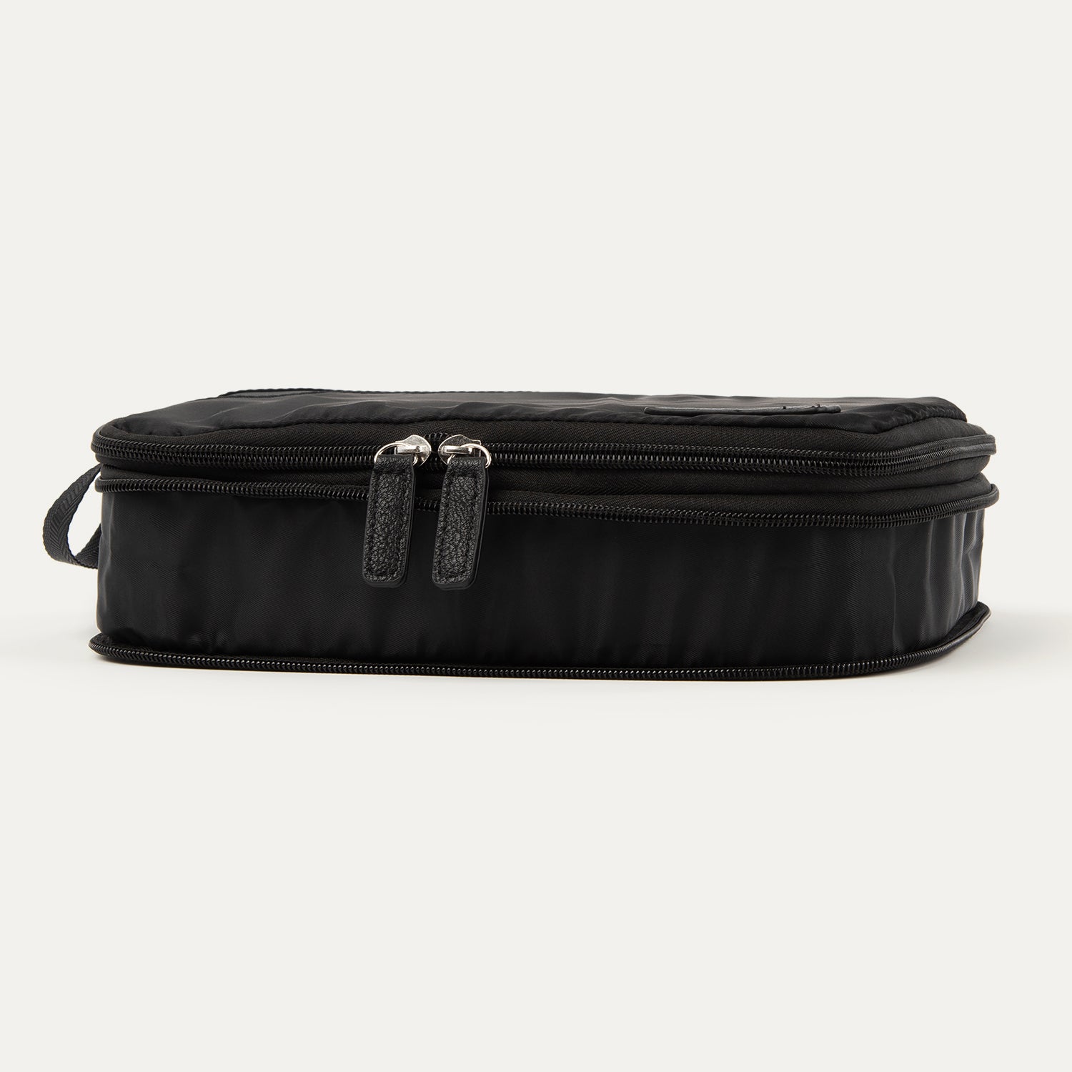 Front compressed view of the Travelpro® Medium Packing Cube in black with dual zipper closures and a side handle.