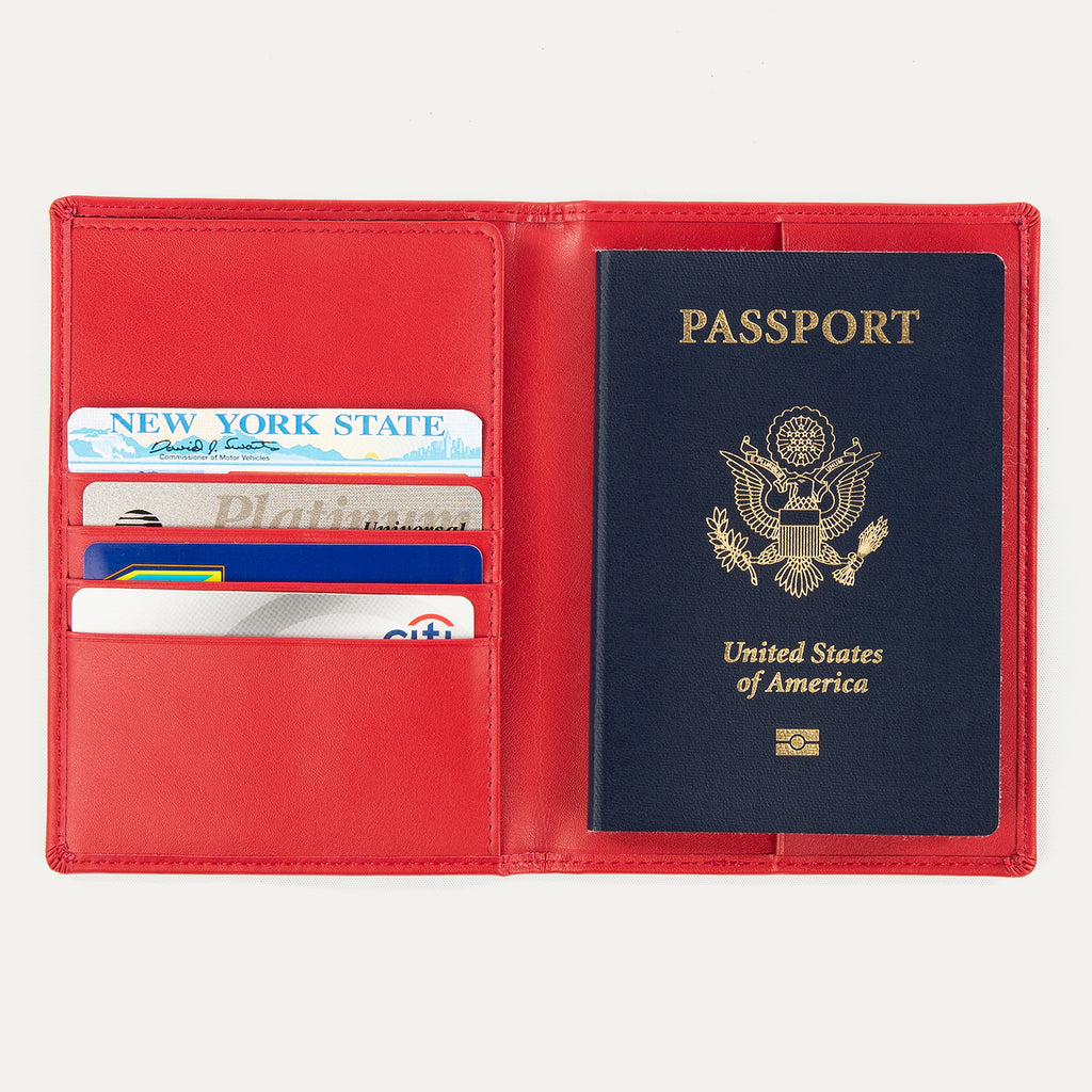 Open red Travelpro® leather passport cover displaying multiple card slots on the left and a passport pocket on the right, shown holding passports and cards.