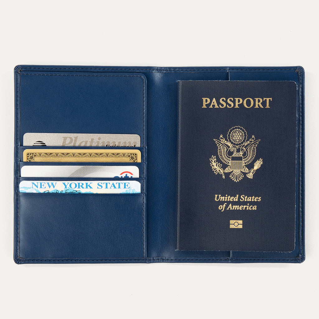 Open view of a navy blue Travelpro passport cover, showing a passport on the right side and card slots on the left holding credit cards and an ID.