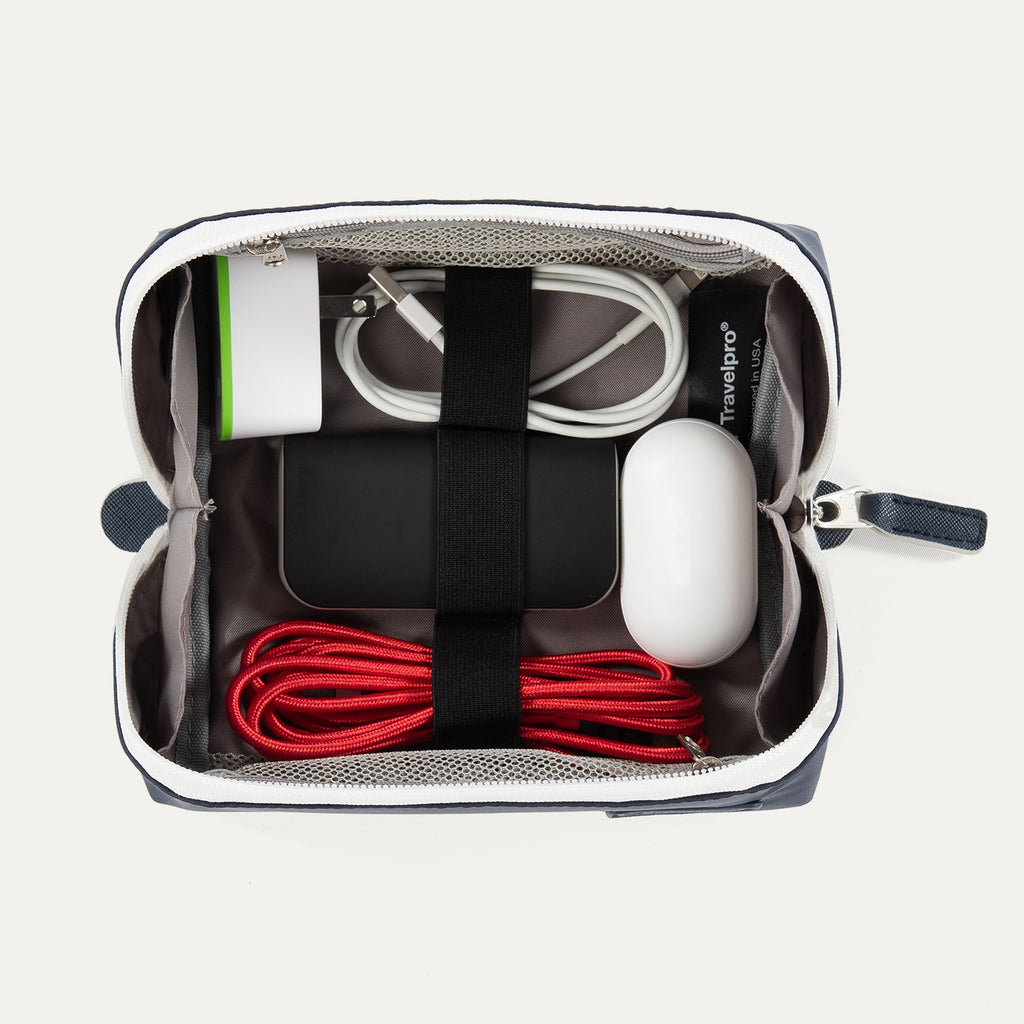 Top view of the Travelpro MaxAccess Cubes™ Large Organizer in navy with a white zipper, packed with electronics secured with interior elastic straps.
