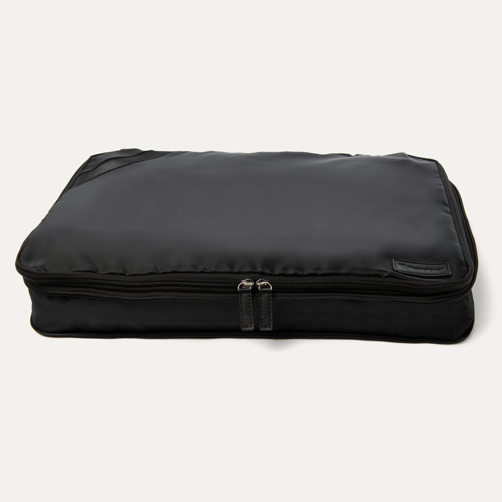 A black Travelpro Essentials XL expandable/compressible packing cube with a zipper.