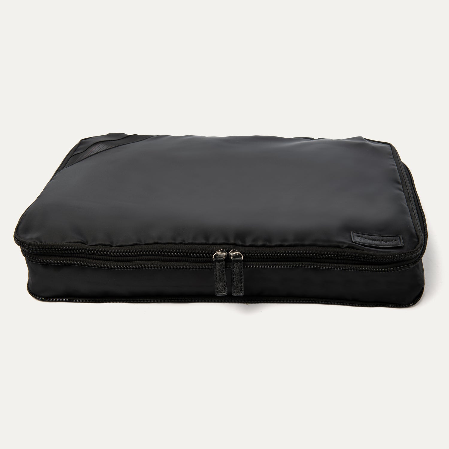 A black Travelpro Essentials XL expandable/compressible packing cube with a zipper.