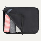 Extra-large Travelpro packing cube in black with mesh panel, partially unzipped to reveal rolled clothing inside.
