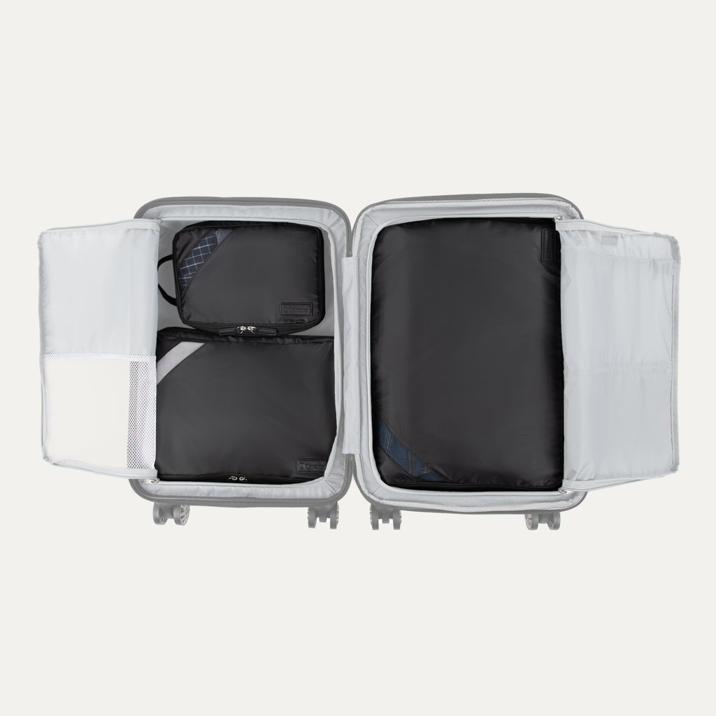 Top view of Travelpro Essentials 3 Pack Expandable/Compressible Packing Cube Set (M/L/XL) in BLACK, with all three cubes packed inside suitcase.
