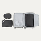 Top view of Travelpro Essentials 3 Pack Expandable/Compressible Packing Cube Set (M/L/XL) in BLACK, with XL packed in suitcase and M and L outside.
