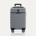 Front view of T+L Compact Carry-On Spinner in Whistler Grey, featuring a smooth telescoping handle and grooved shell design.
