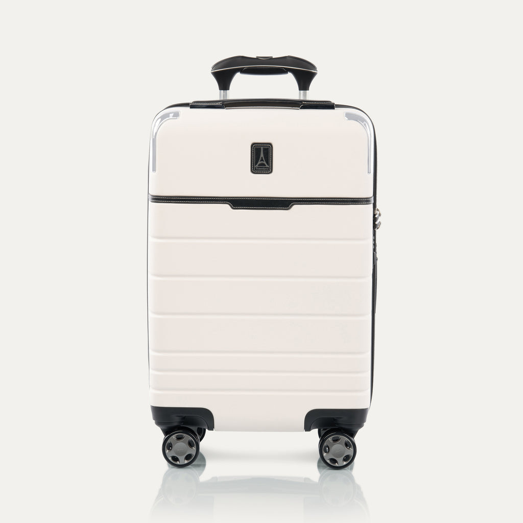 Front view of T+L Carry-On Spinner in White Sand, showing a hard shell with black trim, horizontal grooves, and dual spinner wheels.

