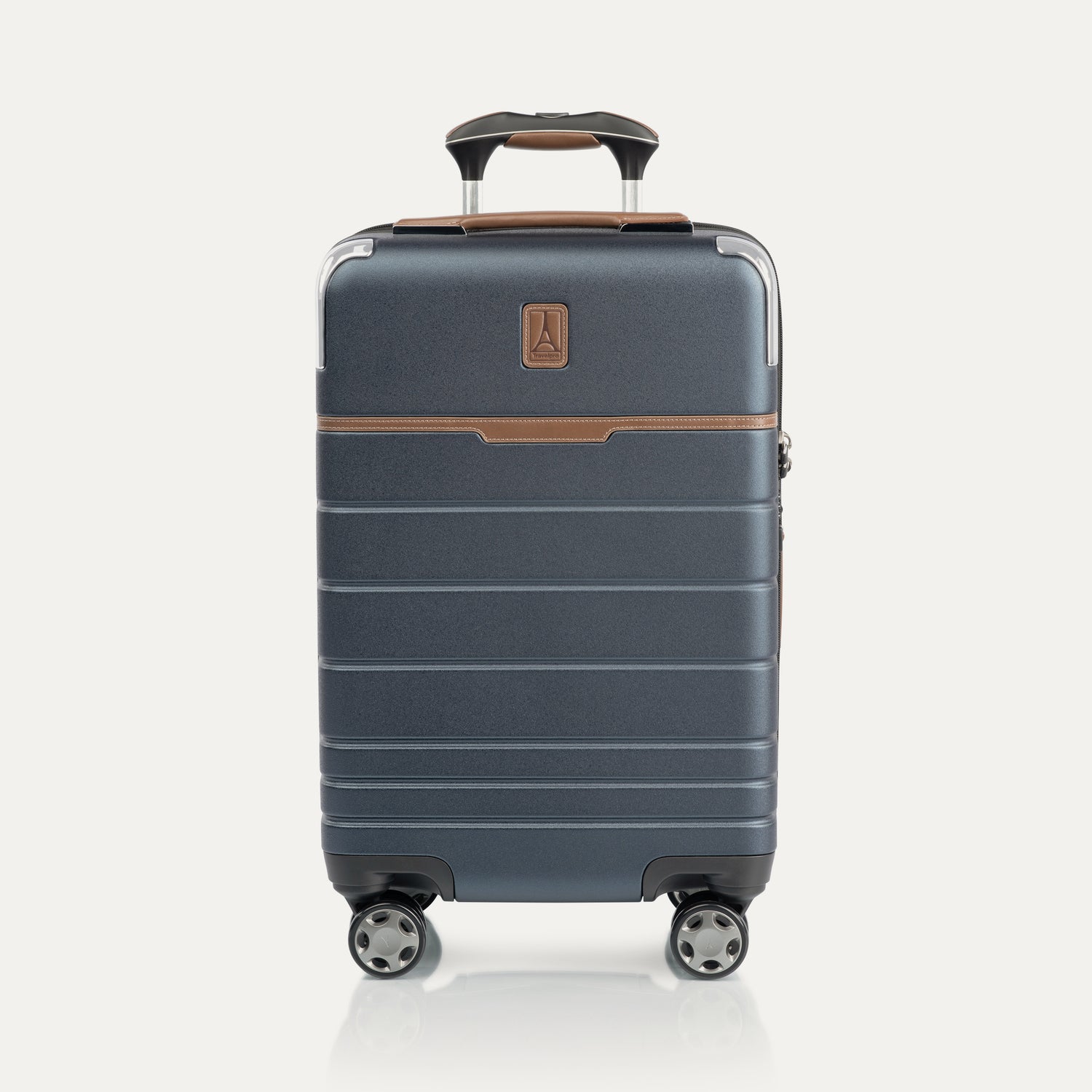 Front view of T+L Carry-On Spinner in Monaco Blue, featuring a matte hard shell, brown contrast trim, horizontal grooves, and dual spinner wheels.
