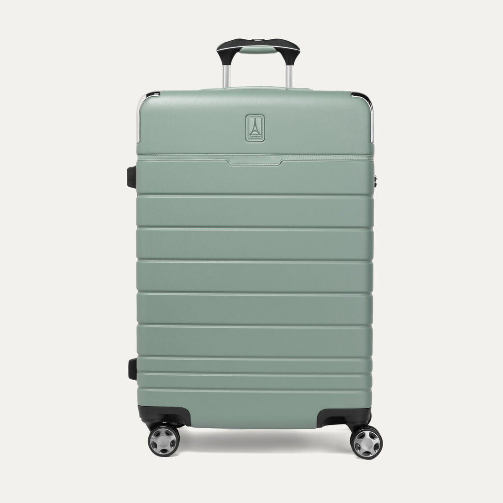 Front view of T+L Medium Check-In Spinner in Center Sage Green, showing a sleek hard shell with horizontal grooves and dual spinner wheels.
