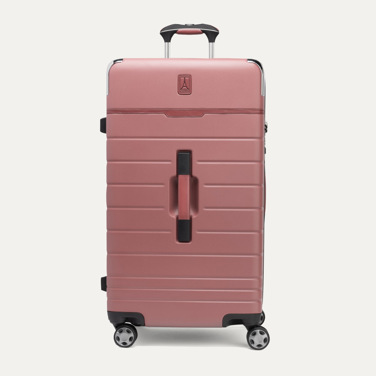 front view of the large check-in trunk spinner in astro dust red, showcasing its durable textured polycarbonate hardshell construction, signature zinc corner armor, premium brown leather trim accents, and four-wheeled spinner system with an extended telescoping handle.