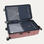 interior view of the open astro dust red travelpro x travel plus leisure large check-in trunk spinner, featuring a spacious split-case design with fully lined navy blue fabric, zippered privacy separator panels with mesh detailing, and premium silver metal zipper pulls.