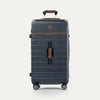 Front view of Travel + Leisure® Large Check-In Expandable Spinner in Monaco Blue, with textured hard shell, contrast brown trim, and dual spinner wheels.