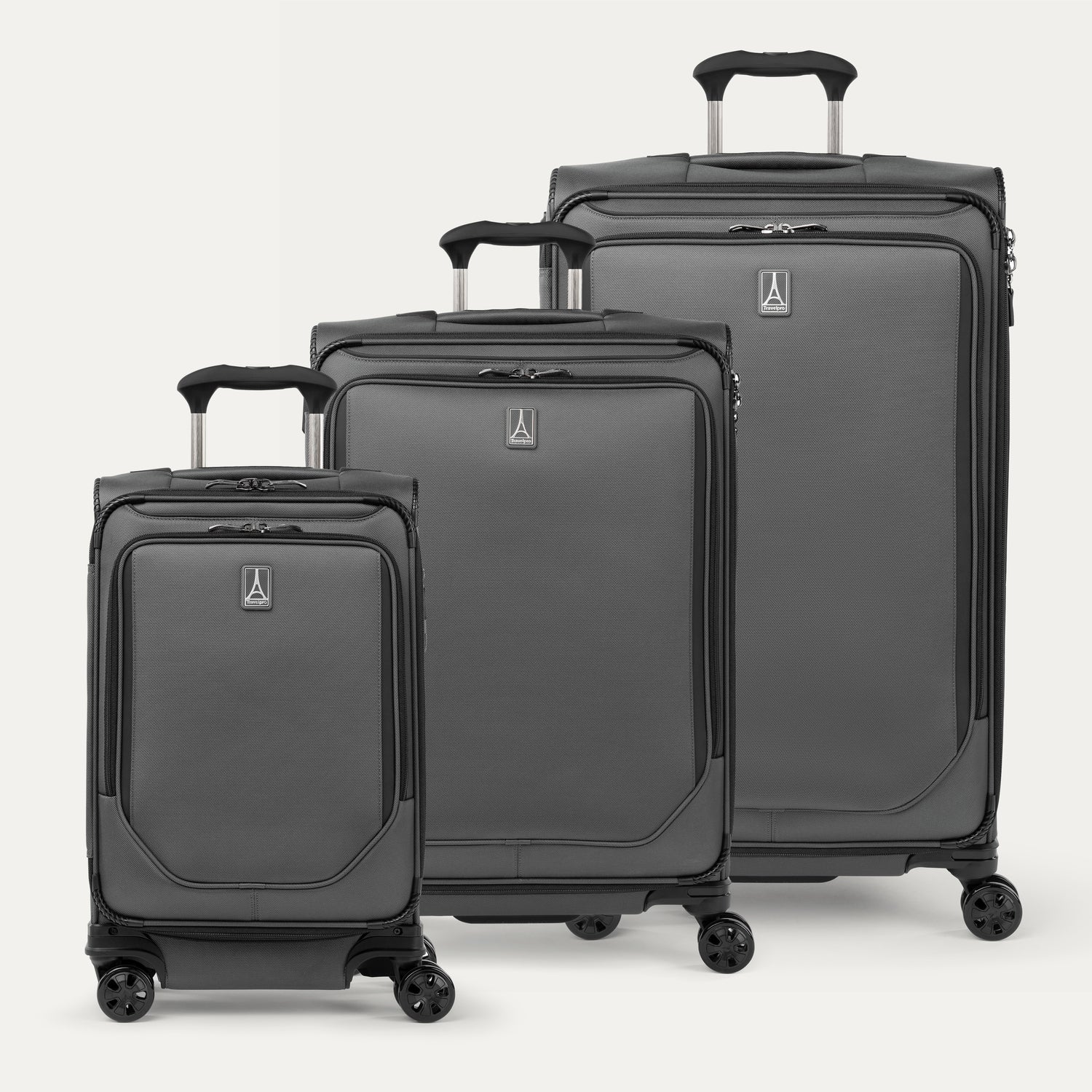 A set of three gray spinner suitcases, including a carry-on size, medium size, and large size, aligned in a row with the telescopic handles extended.