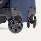 Close-up of a navy blue suitcase with black wheels on a white background
