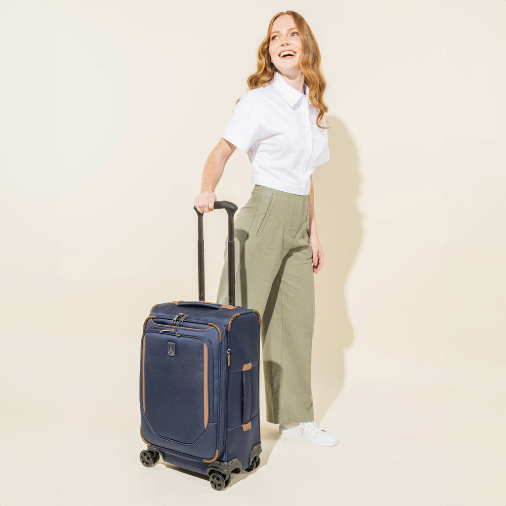 Person holding the Crew™ Classic Carry-on Expandable Spinner in Patriot Blue.

