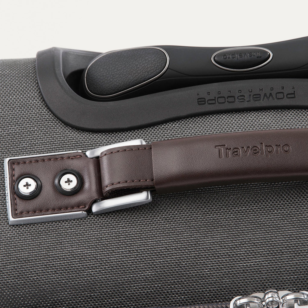 Close-up of a suitcase handle with a brown leather strap 