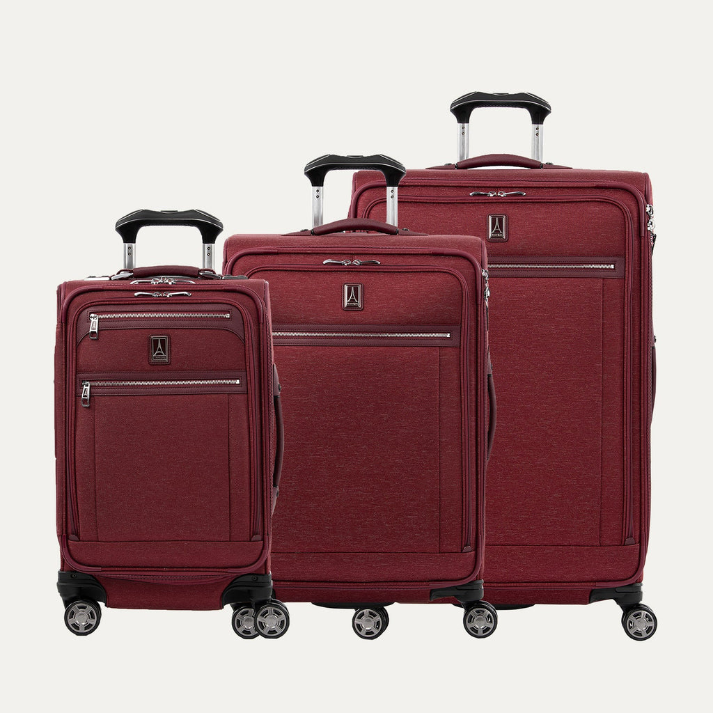 A set of three expandable spinner luggage bags in red color, including a carry-on size and two larger sizes, with chrome zippers and a leather accent on the front pocket.