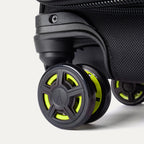 Detailed close-up of the spinner wheels on the Platinum Elite Neon Shadow Carry-On in black, highlighting the durable wheel construction and the signature neon green accents on the center wheel caps.