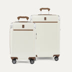 A set of two Platinum Elite hardside spinner suitcases in cream white , including a carry-on and a medium check-in size, featuring brown leather trim and aluminum corner protectors.
