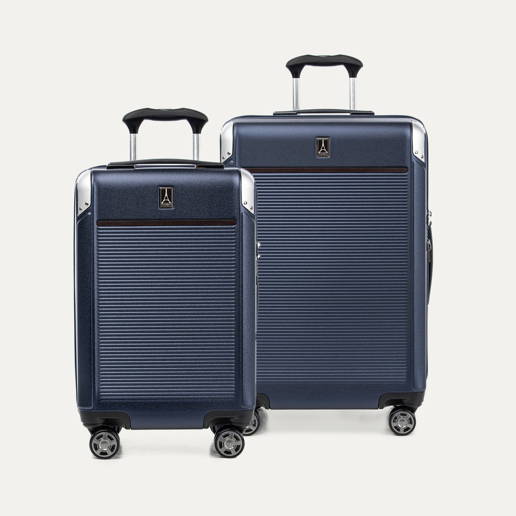 A set of two navy blue hardside spinner suitcases, one carry-on and one medium check-in size on a white background