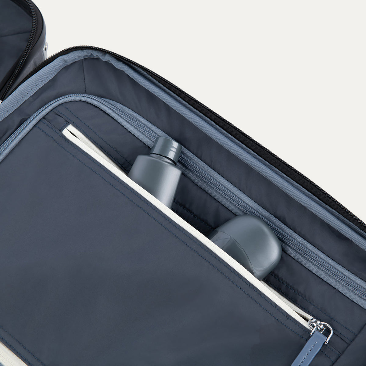 Interior view of Travelpro Platinum Elite Compact Carry-On Hardside Spinner in Shadow Black, showing zippered pocket with visible travel-size toiletries.
