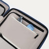 Interior view of Travelpro Platinum Elite Compact Carry-On Hardside Spinner in Dark Sky Blue, showing zippered pocket with visible travel-size toiletries.
