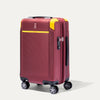 Front view of Travelpro x Surgeon Check-In Spinner in Daring Red with yellow corner guards and textured front panel.

