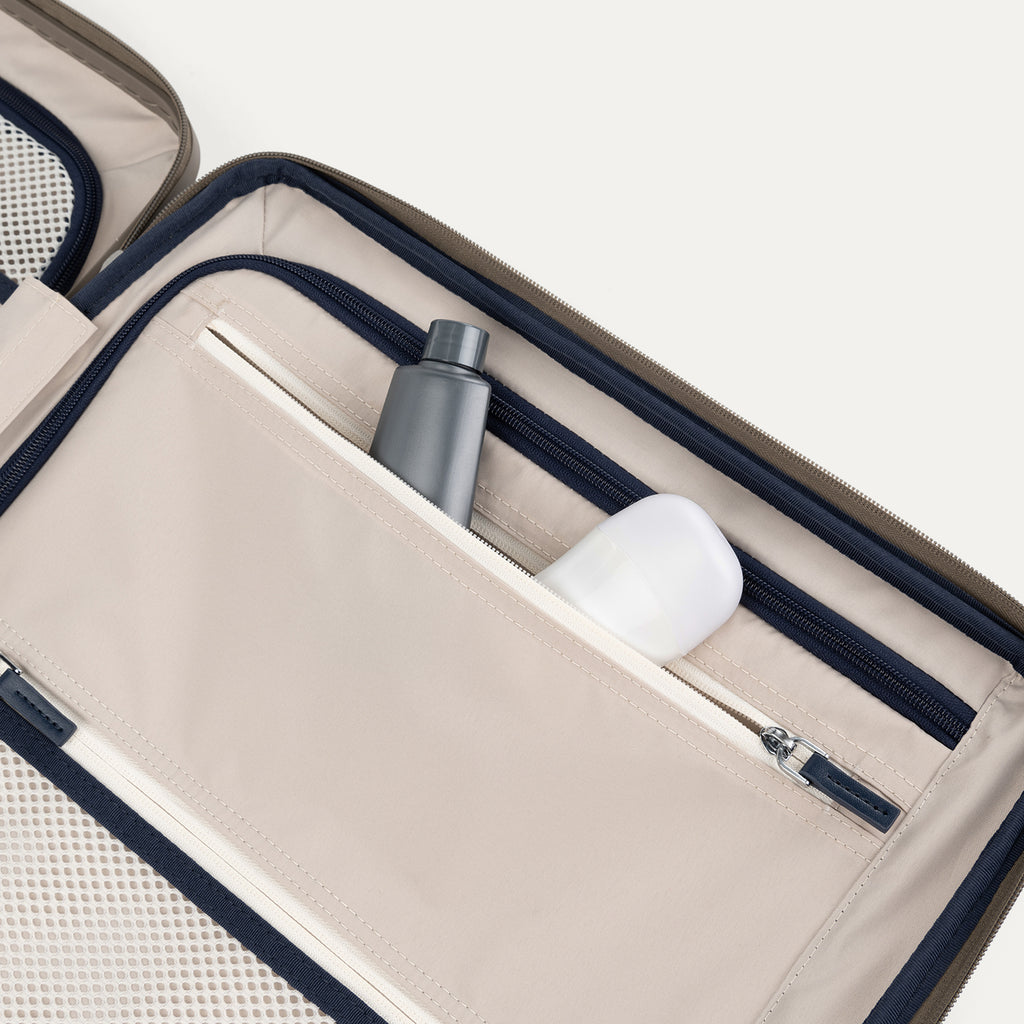 Interior view of Travelpro Platinum Elite  Hardside Spinner in Metallic Sand, showing zippered pocket with visible travel-size toiletries