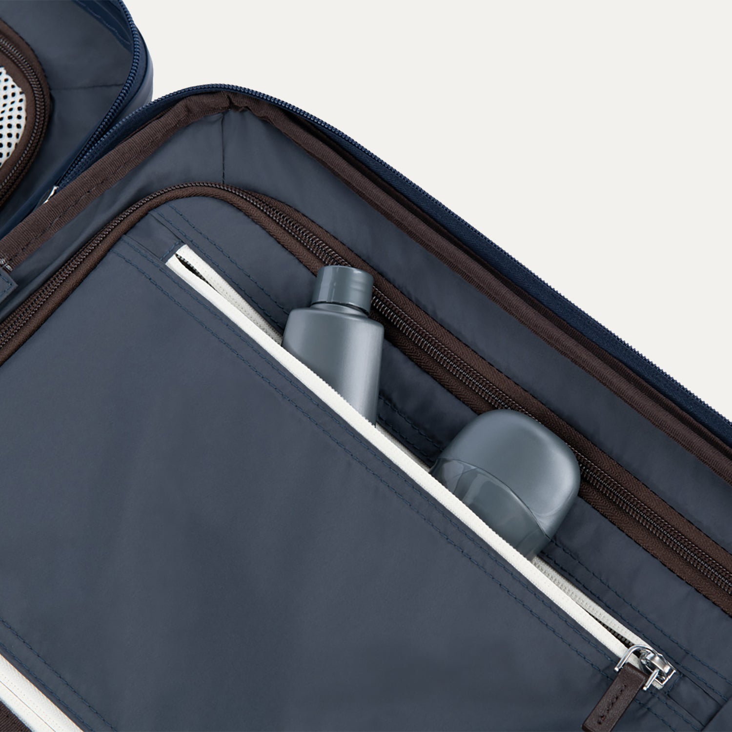 Interior view of Travelpro Platinum Elite Compact Carry-On Hardside Spinner in True Navy, showing zippered pocket with visible travel-size toiletries.


