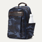Angled front view of Travelpro Platinum Elite Slim Backpack in Navy Camouflage with zippered front pocket and side water bottle holder.
