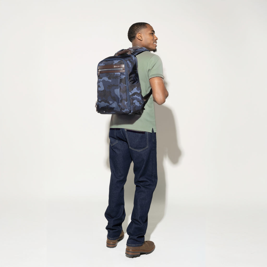 Man wearing the Platinum® Elite Slim Backpack in Camouflage, showcasing its sleek design, adjustable shoulder straps, and front zippered pocket
