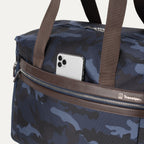  Close-up view of Platinum® Elite Soft Duffel in Camouflage, showing an exterior pocket with a smartphone partially tucked inside.

