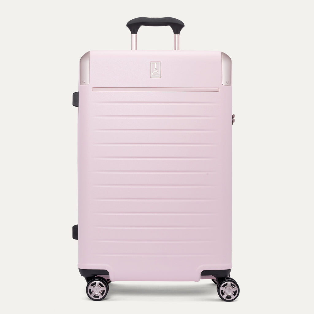  front view of the Travelpro Platinum Elite Medium Check-In Hardside Spinner in Powder Pink, featuring a durable polycarbonate shell with polished aluminum corner armor, an extended telescopic handle, and multi-directional wheels against a clean off-white background.